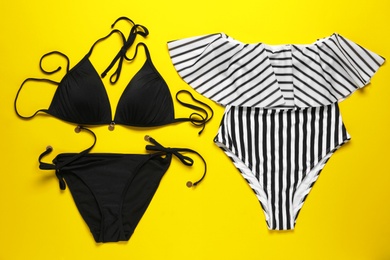 Photo of Flat lay composition with two stylish swimsuits on yellow background