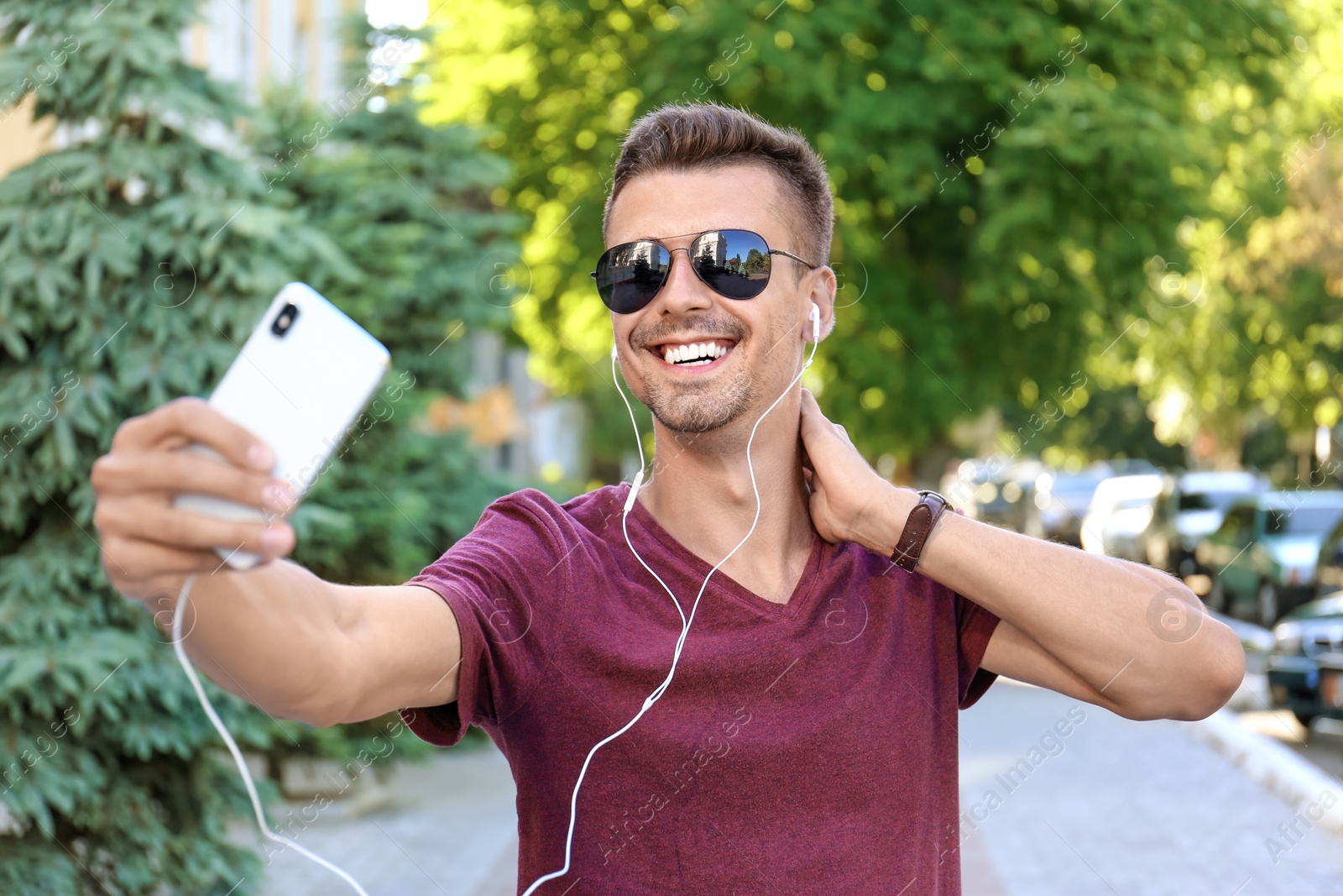 Photo of Young man in sunglasses taking selfie outdoors