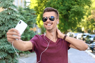 Young man in sunglasses taking selfie outdoors