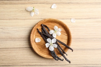 Flat lay composition with aromatic vanilla sticks and flowers on wooden background