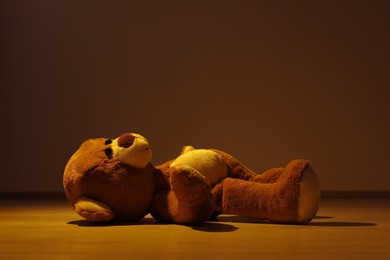 Photo of Cute teddy bear left on floor in dark room