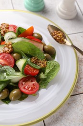 Delicious salad with vegetables, olives and grain mustard on light table