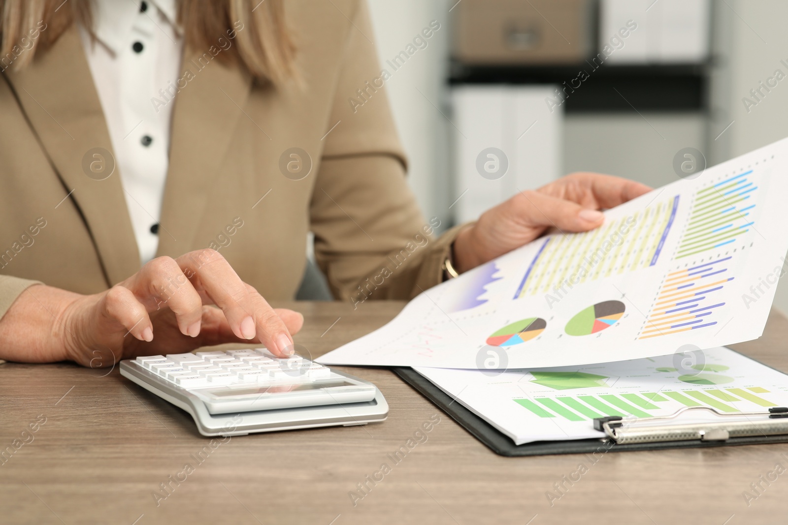 Photo of Accountant using calculator at wooden desk in office, closeup