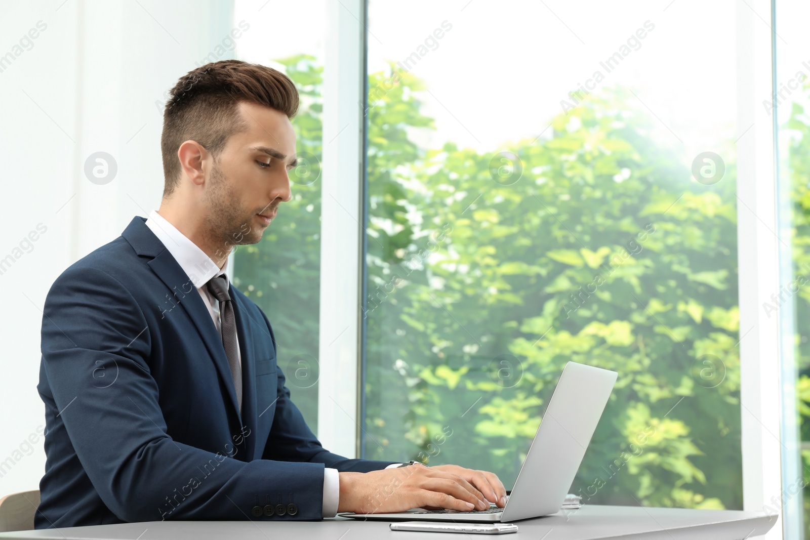 Photo of Man in office wear using laptop at table indoors