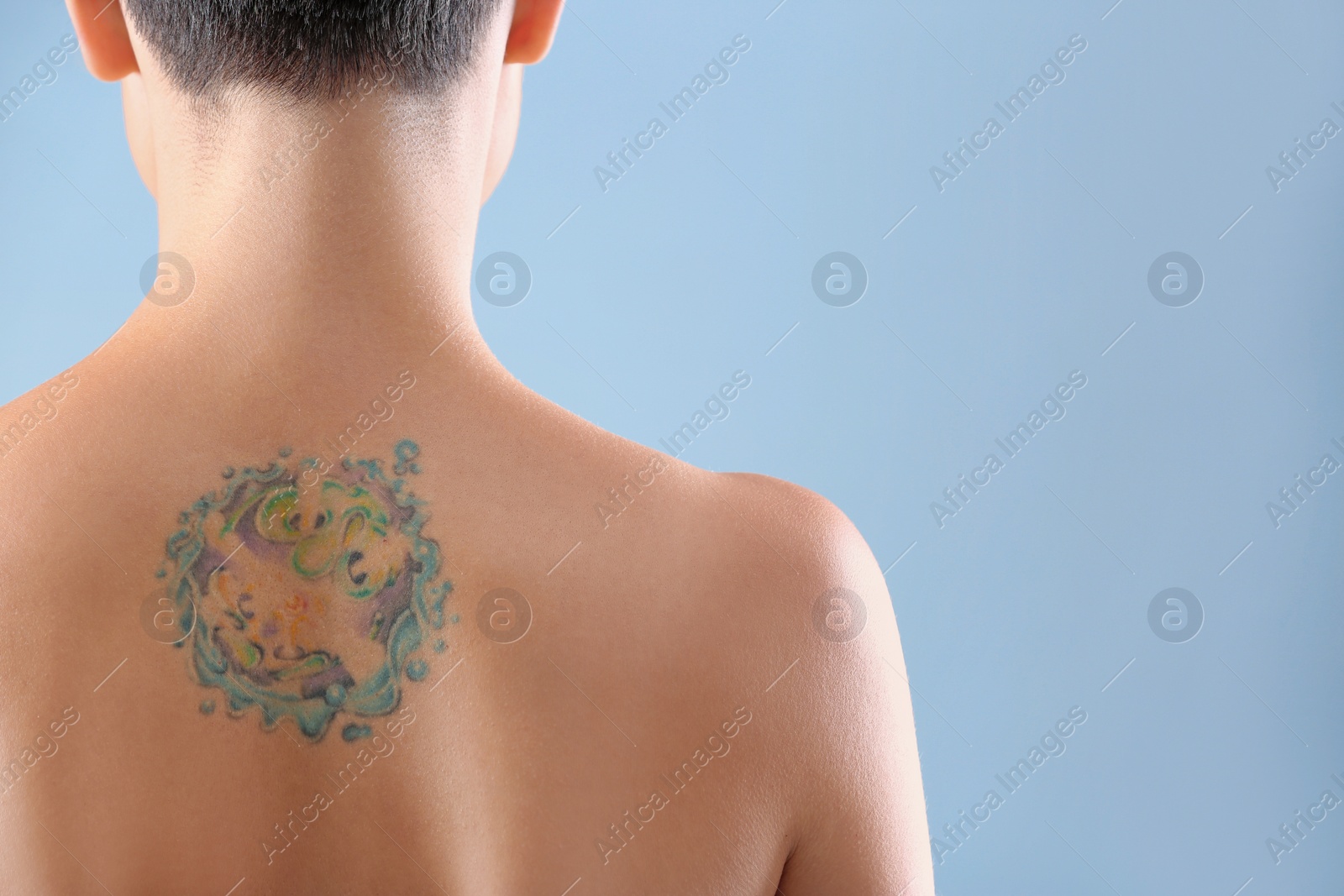 Photo of Beautiful tattoo on female back against color background. Space for text