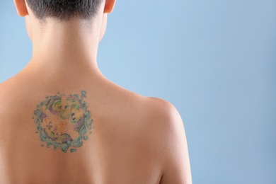 Beautiful tattoo on female back against color background. Space for text