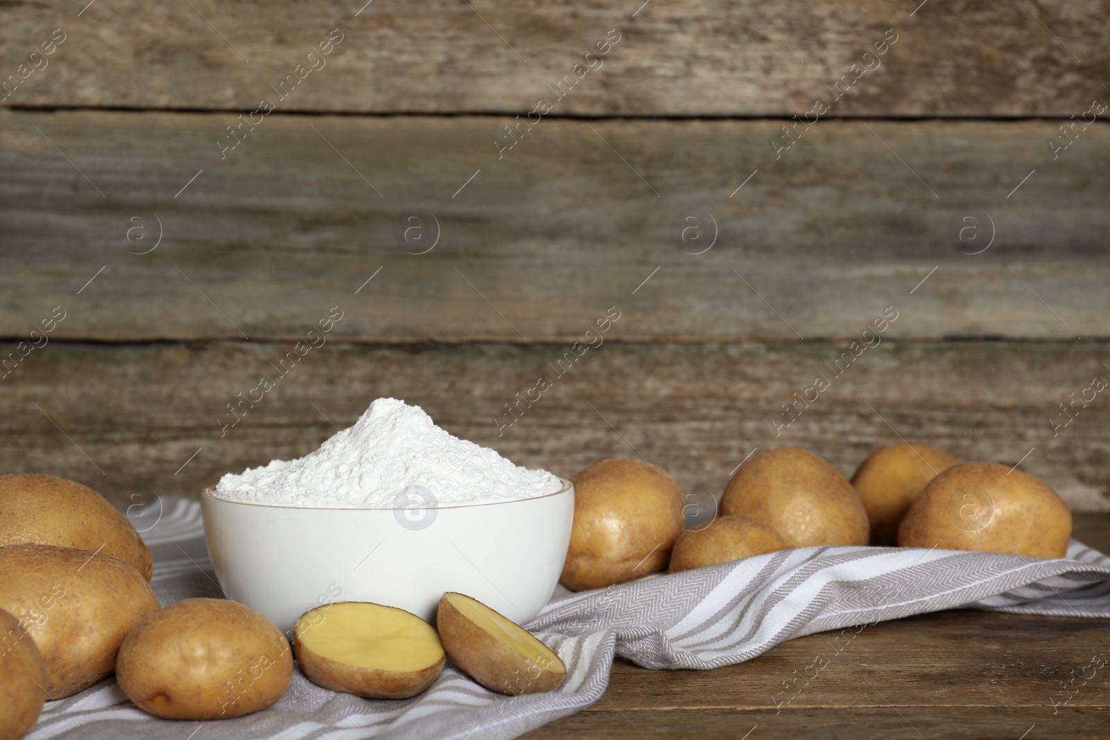 Photo of Starch and fresh raw potatoes on wooden table. Space for text