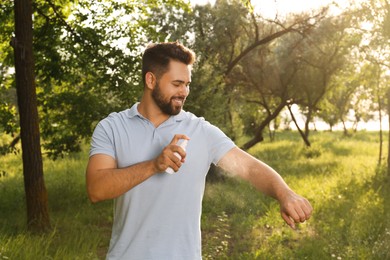 Photo of Man applying insect repellent on arm in park. Tick bites prevention