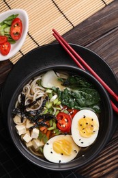 Photo of Delicious vegetarian ramen served on wooden table, top view. Noodle soup