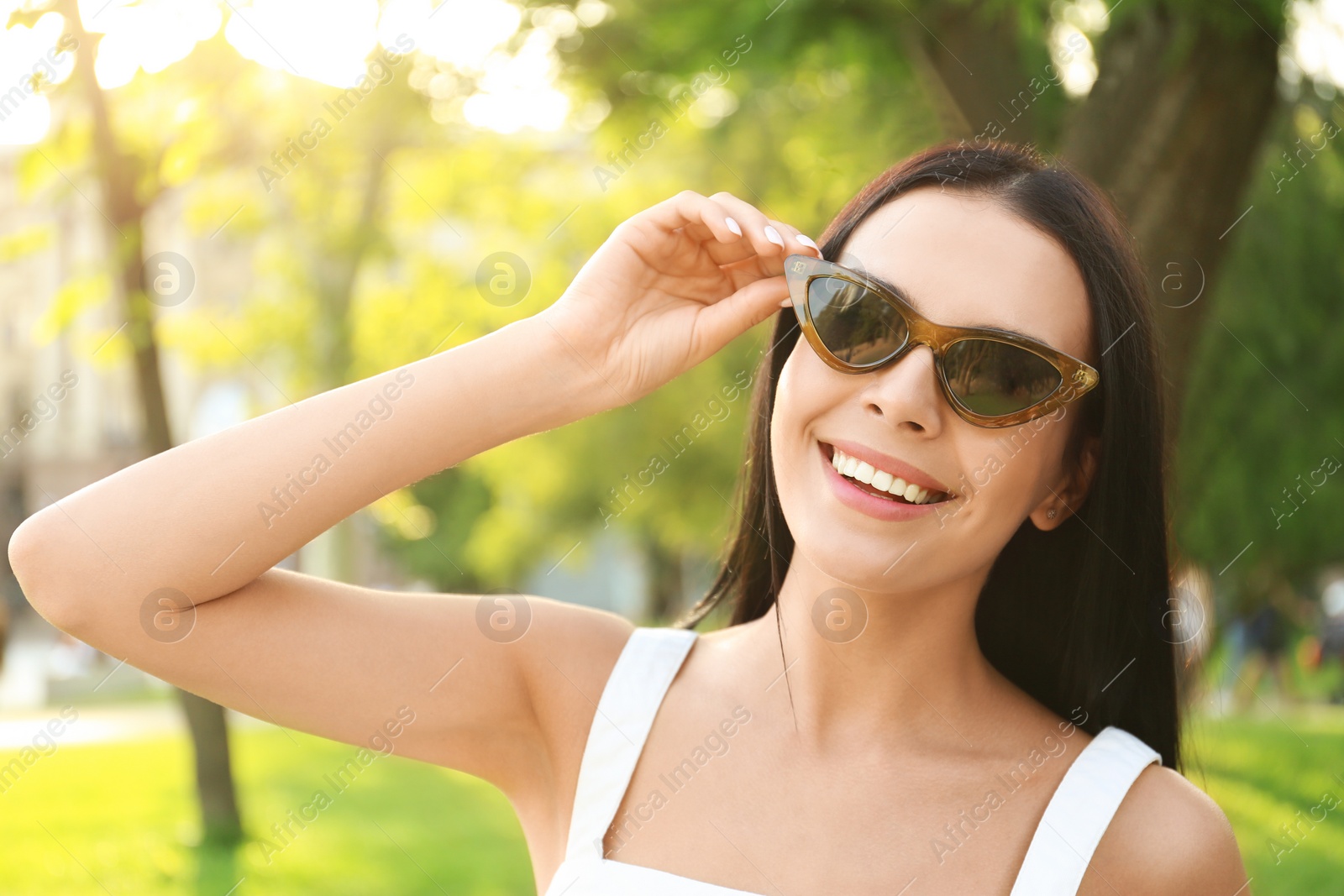 Photo of Beautiful young woman wearing stylish sunglasses in park