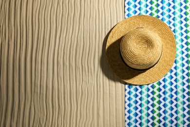 Photo of Bright towel and hat on sand, top view with space for text. Beach objects