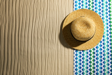 Bright towel and hat on sand, top view with space for text. Beach objects