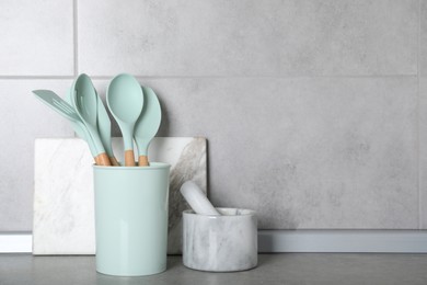 Set of kitchen utensils, mortar with pestle and cutting board on grey table. Space for text