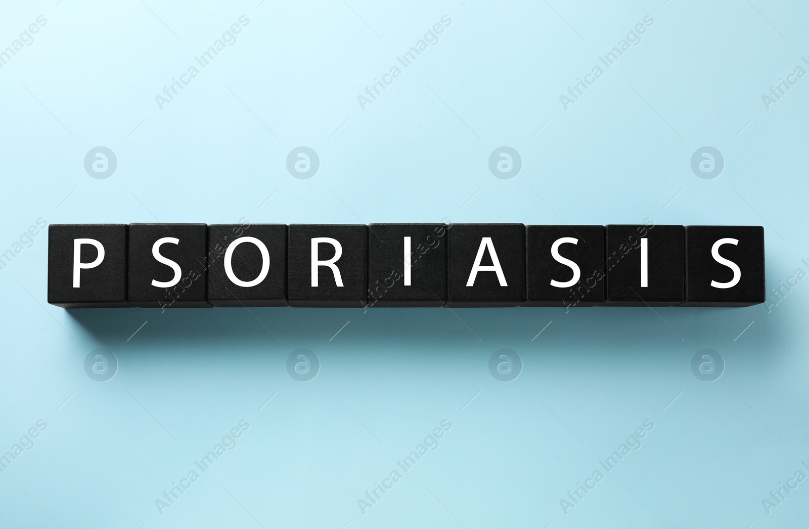 Photo of Word Psoriasis made of black wooden cubes with letters on light blue background, top view