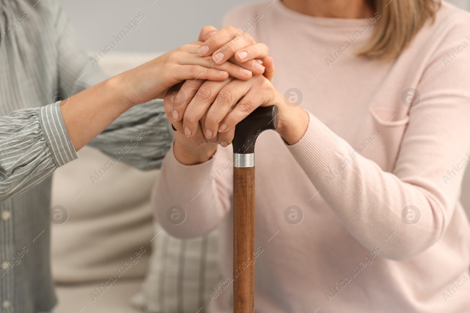Photo of Mature lady with walking cane and young woman indoors, closeup