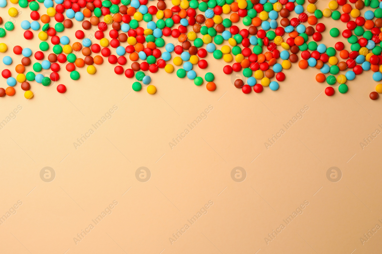 Photo of Tasty colorful candies on beige background, flat lay. Space for text