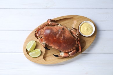Photo of Delicious boiled crab served with lime and sauce on white wooden table, top view