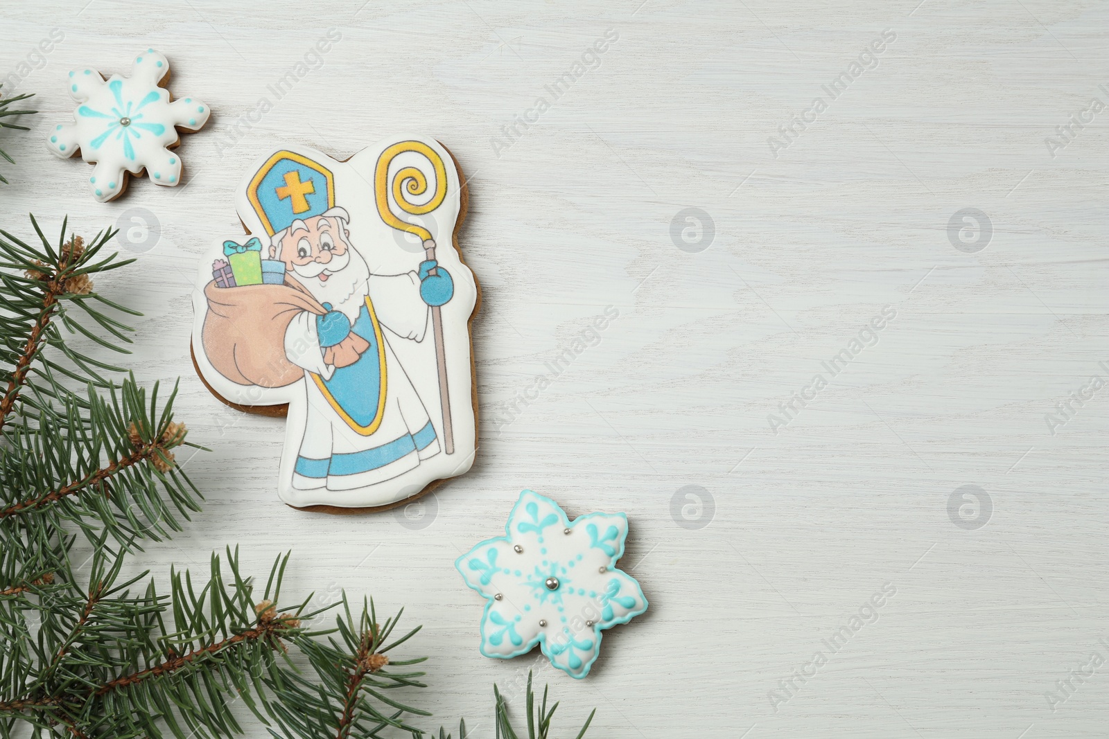 Photo of Delicious gingerbread cookies on white wooden table, flat lay with space for text. St. Nicholas Day celebration