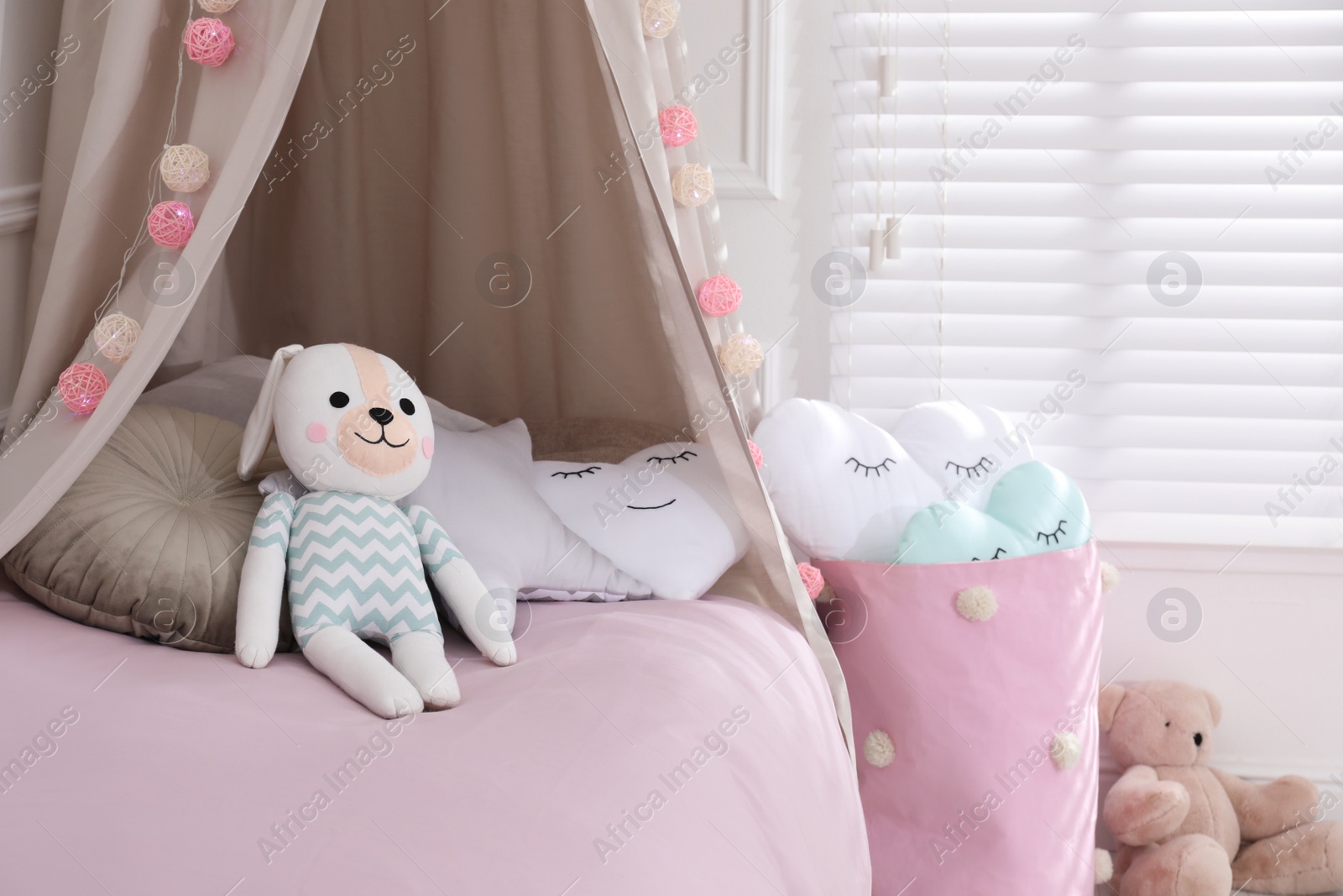 Photo of Cute toy bunny on bed in stylish playroom. Interior design