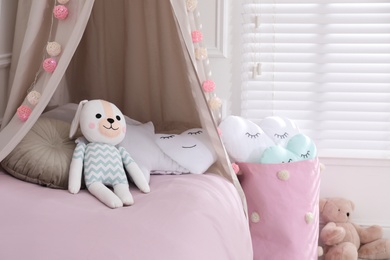 Cute toy bunny on bed in stylish playroom. Interior design