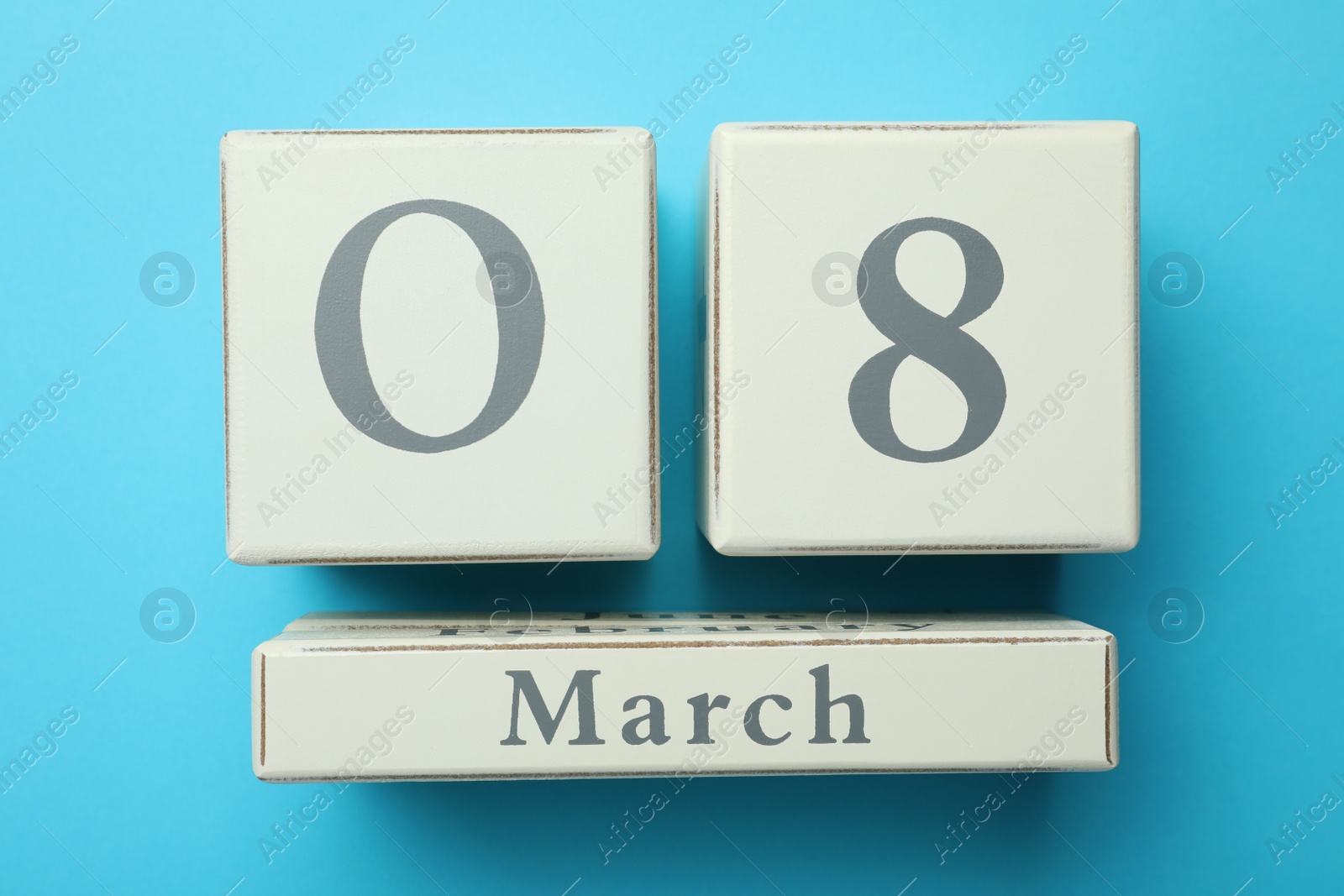 Photo of Wooden block calendar with date 8th of March on light blue background, flat lay. International Women's Day