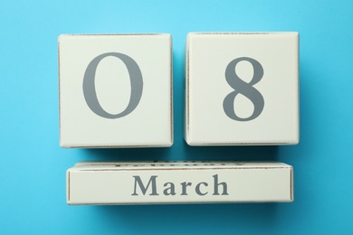 Wooden block calendar with date 8th of March on light blue background, flat lay. International Women's Day