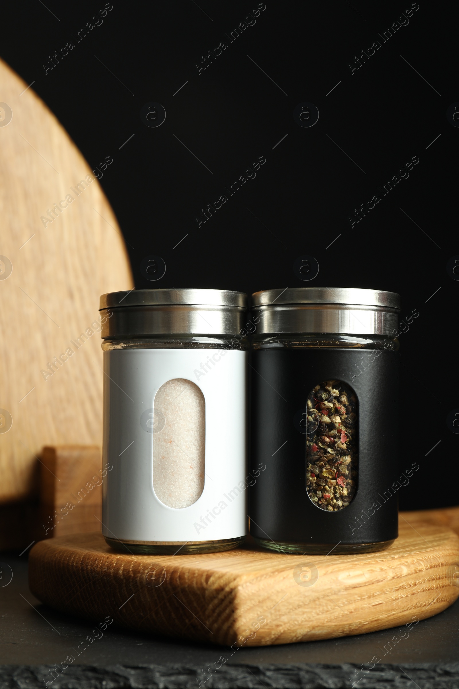 Photo of Salt and pepper shakers on table against black background