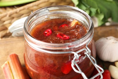 Tasty rhubarb sauce in glass jar on table, closeup view