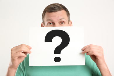Photo of Man holding paper with question mark on white background