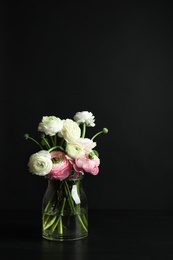 Photo of Glass vase with beautiful ranunculus flowers on black background