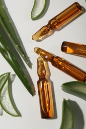 Skincare ampoules and aloe leaves on white background, flat lay