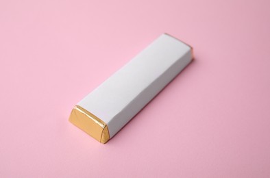 Photo of Tasty chocolate bar in package on pink background