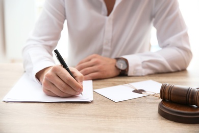 Notary working with papers and judge gavel on table in office, closeup. Law and justice concept