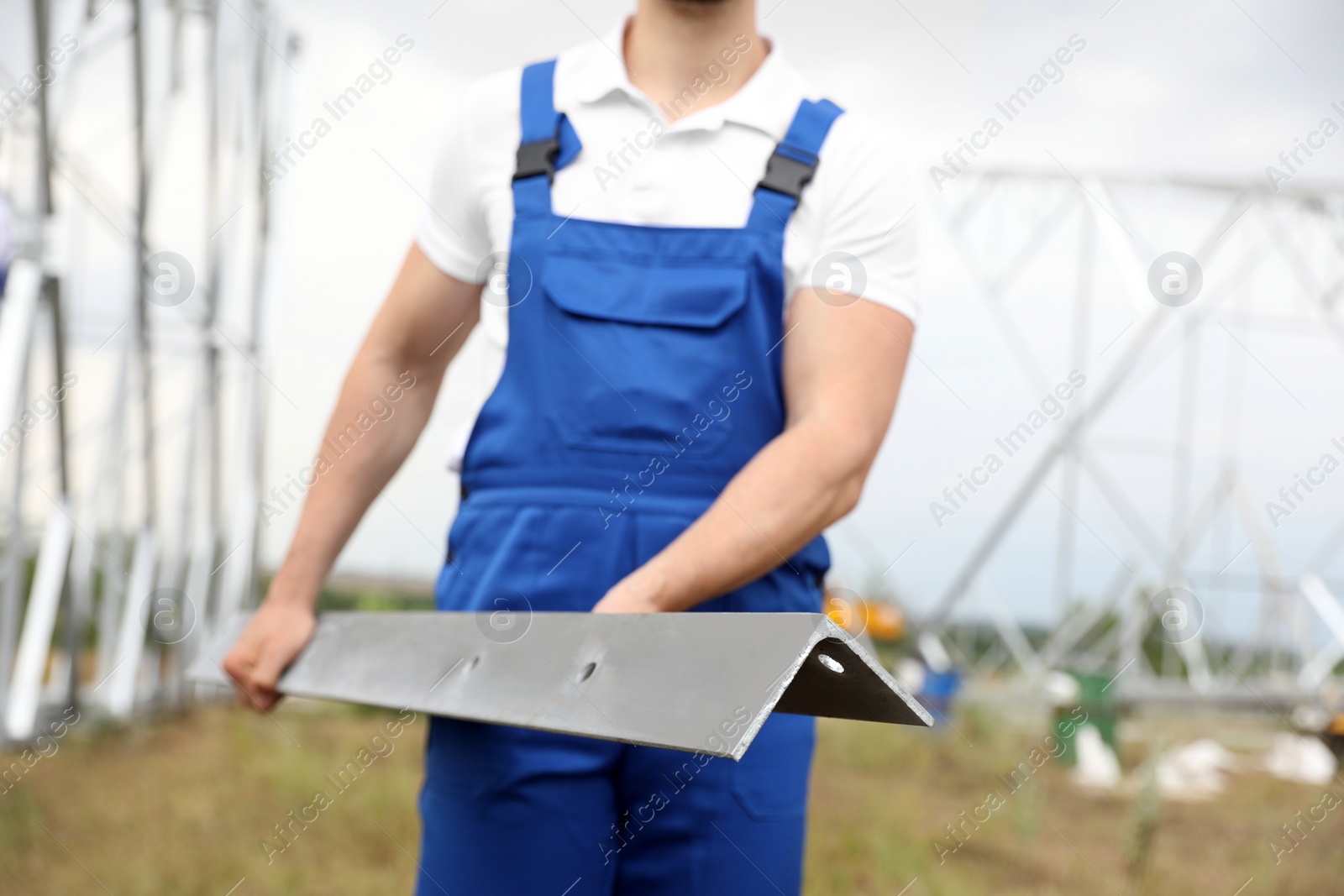 Photo of Worker with detail from high voltage tower construction on building site, closeup. Installation of electrical substation