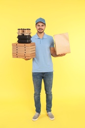 Young courier with different orders on color background. Food delivery service