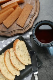 Photo of Delicious quince paste, bread and cup of tea on grey textured table, flat lay