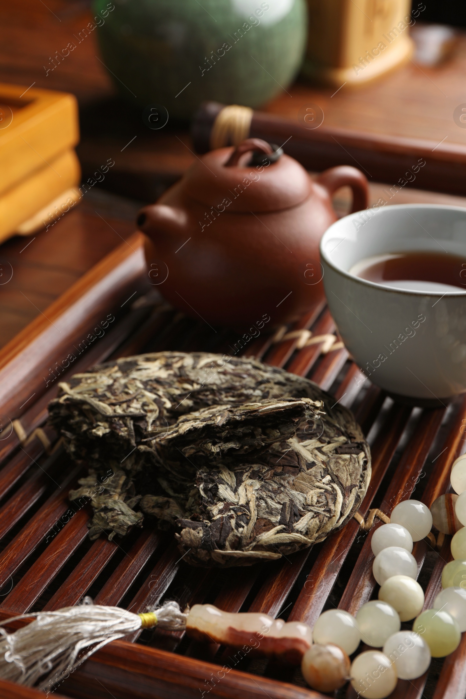 Photo of Aromatic pu-erh tea and prayer beads on wooden tray, closeup. Traditional ceremony