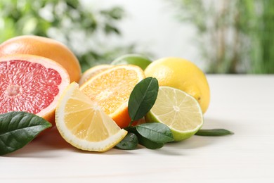 Different cut and whole citrus fruits on white wooden table, closeup. Space for text