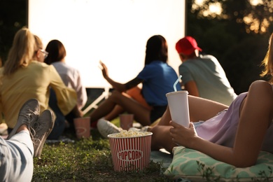 Photo of Young people with popcorn and drink watching movie in open air cinema, closeup