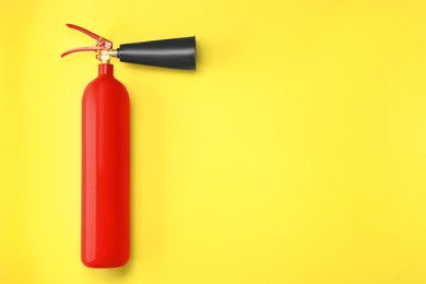 Fire extinguisher on yellow background, top view. Space for text