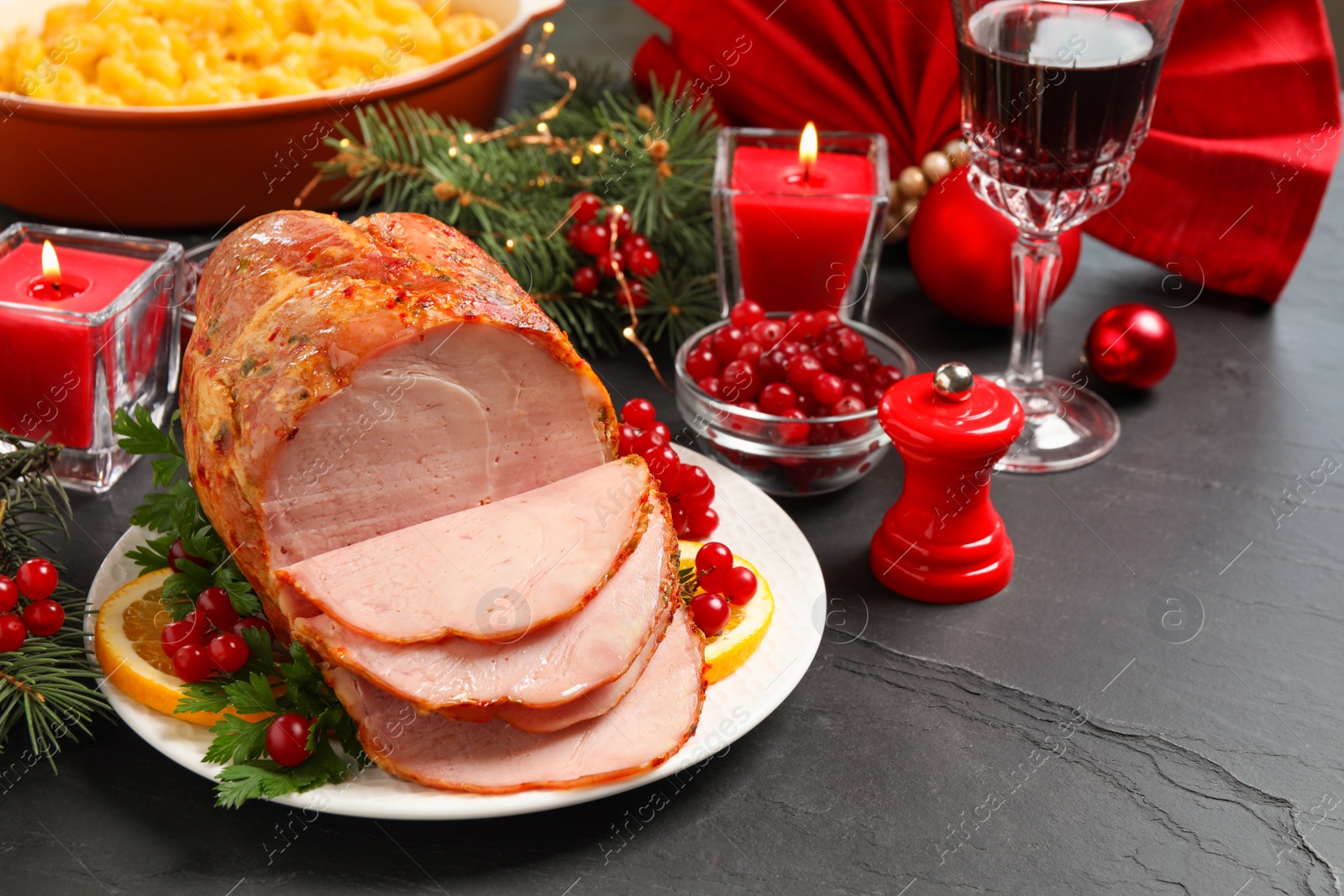 Photo of Delicious Christmas ham served with garnish on dark table