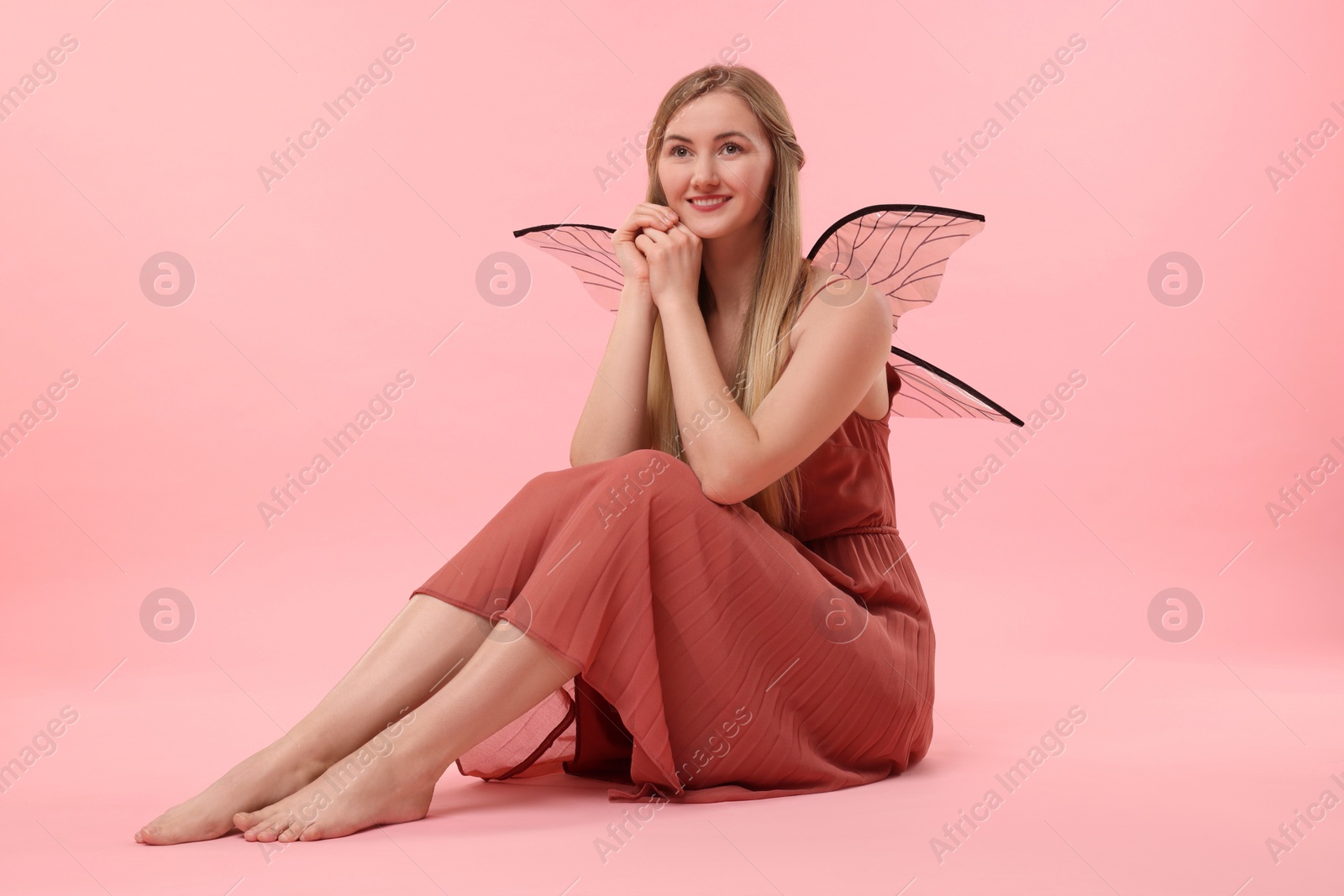 Photo of Beautiful girl in fairy costume with wings on pink background