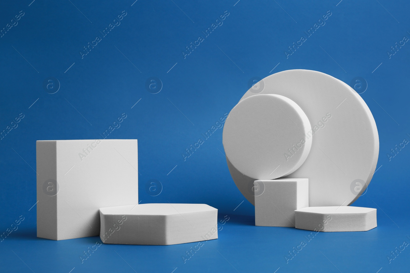 Photo of Product photography props. Podiums of different geometric shapes on blue background