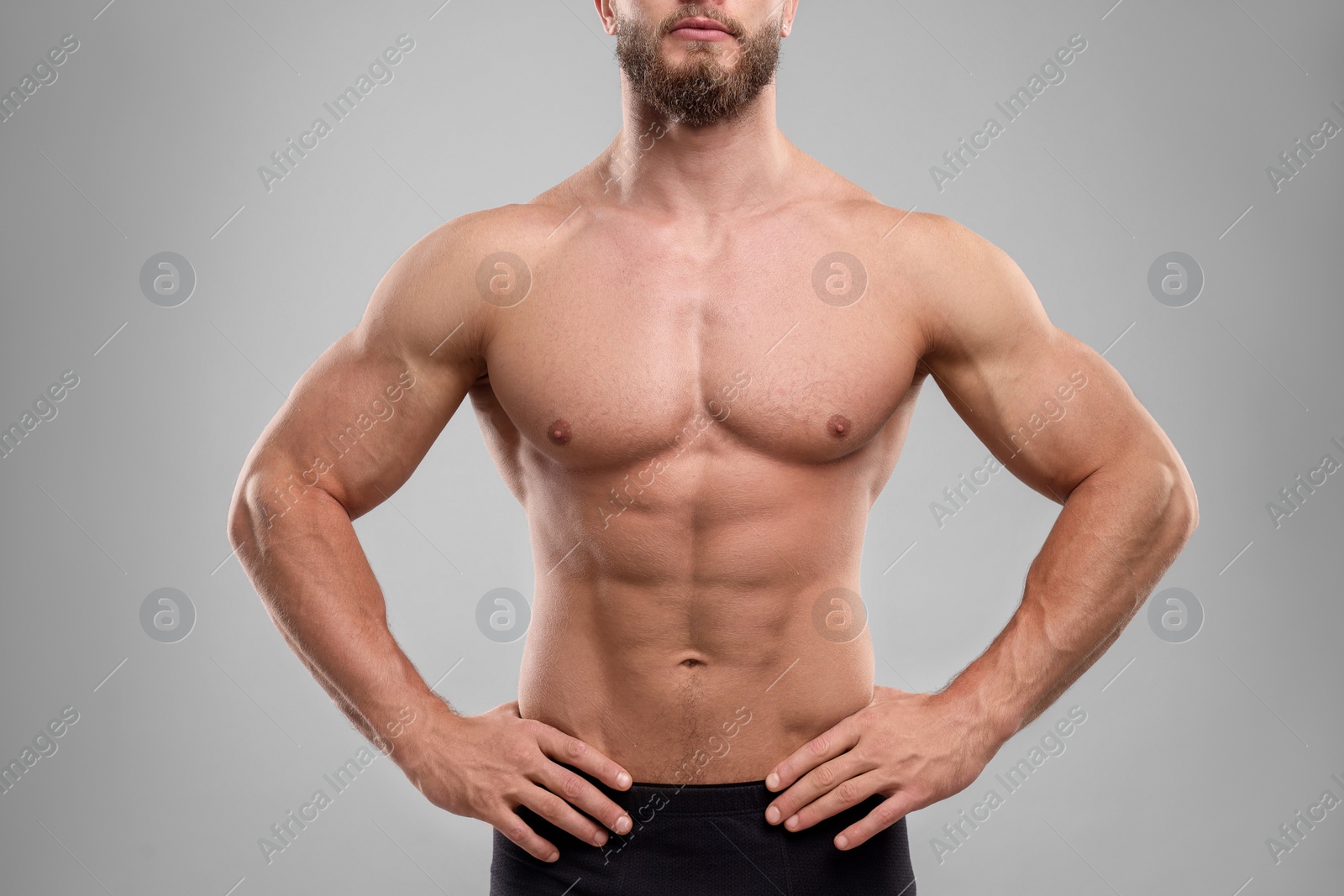 Photo of Muscular man showing abs on light grey background, closeup. Sexy body