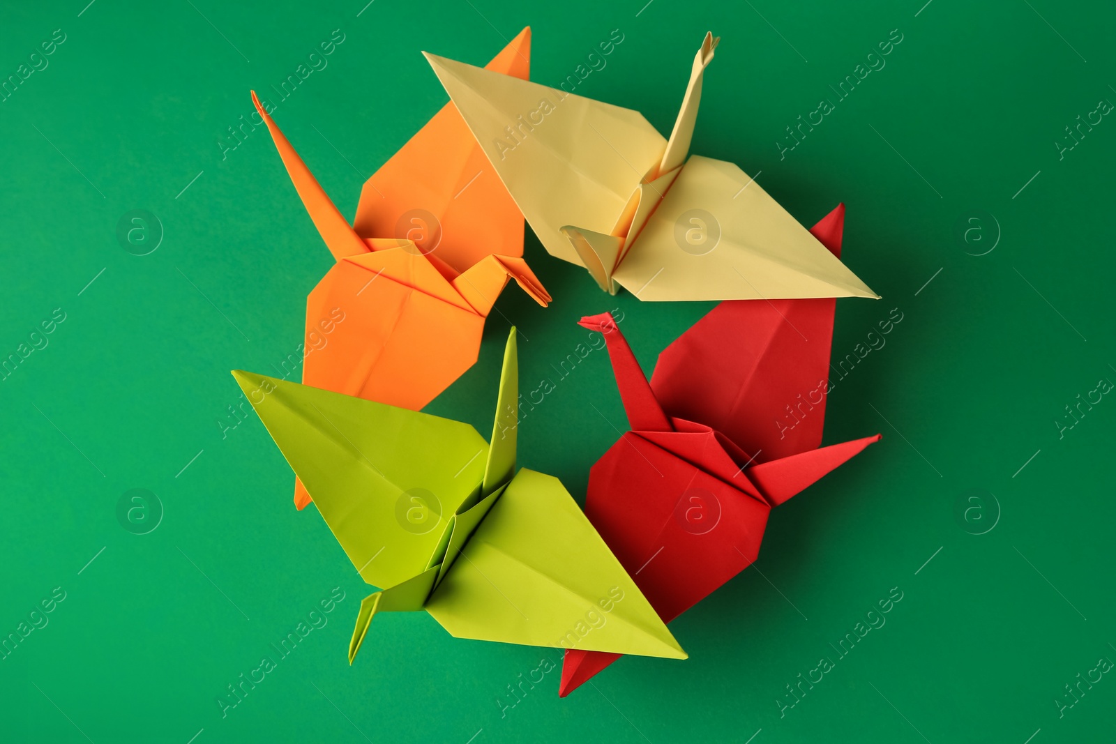 Photo of Colorful paper origami cranes on green background, flat lay