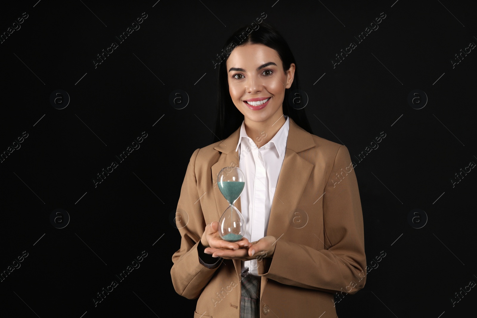 Photo of Businesswoman holding hourglass on black background. Time management