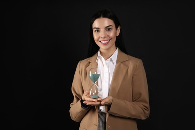 Photo of Businesswoman holding hourglass on black background. Time management