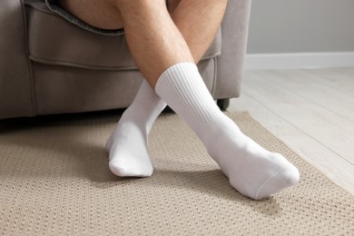 Photo of Man in stylish white socks in armchair indoors, closeup