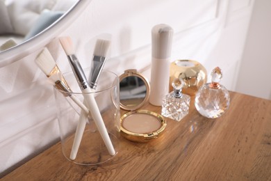 Luxury perfume bottles, cosmetics and accessories on wooden dressing table indoors
