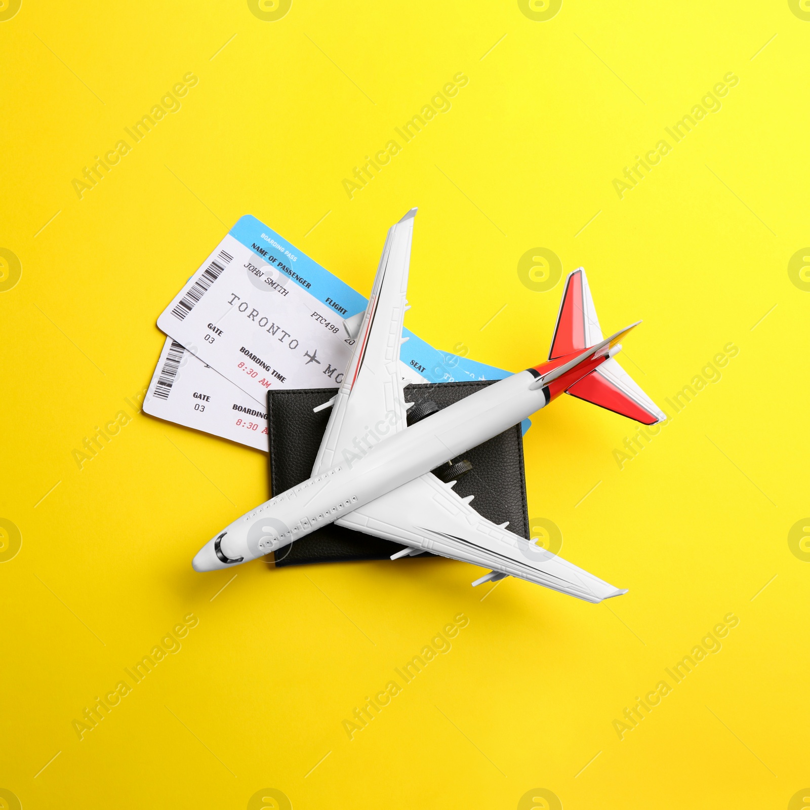Photo of Toy airplane and passport with tickets on yellow background, flat lay